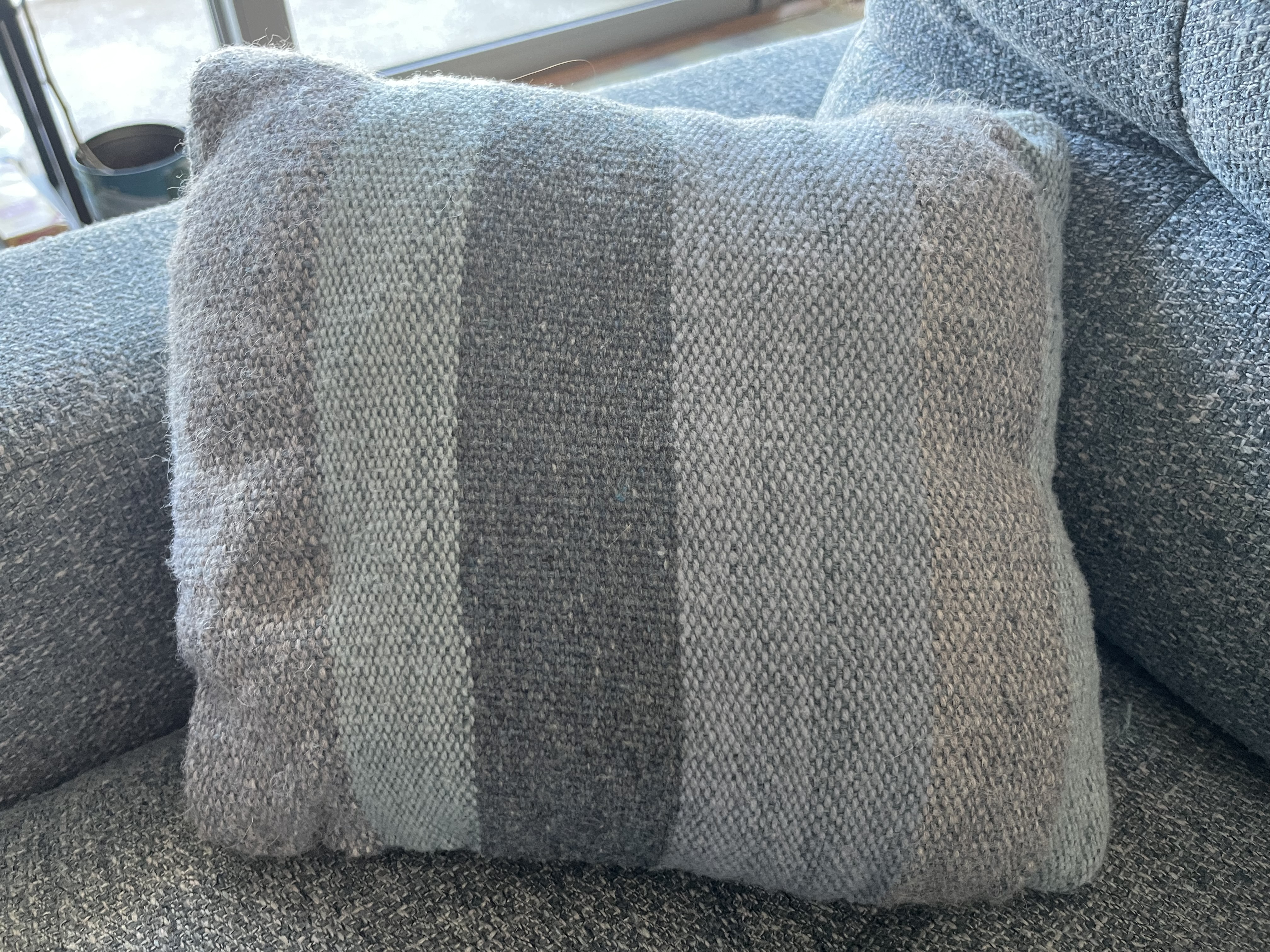 Phot0 of one finished pillow, there are large stripes of blue and gray.